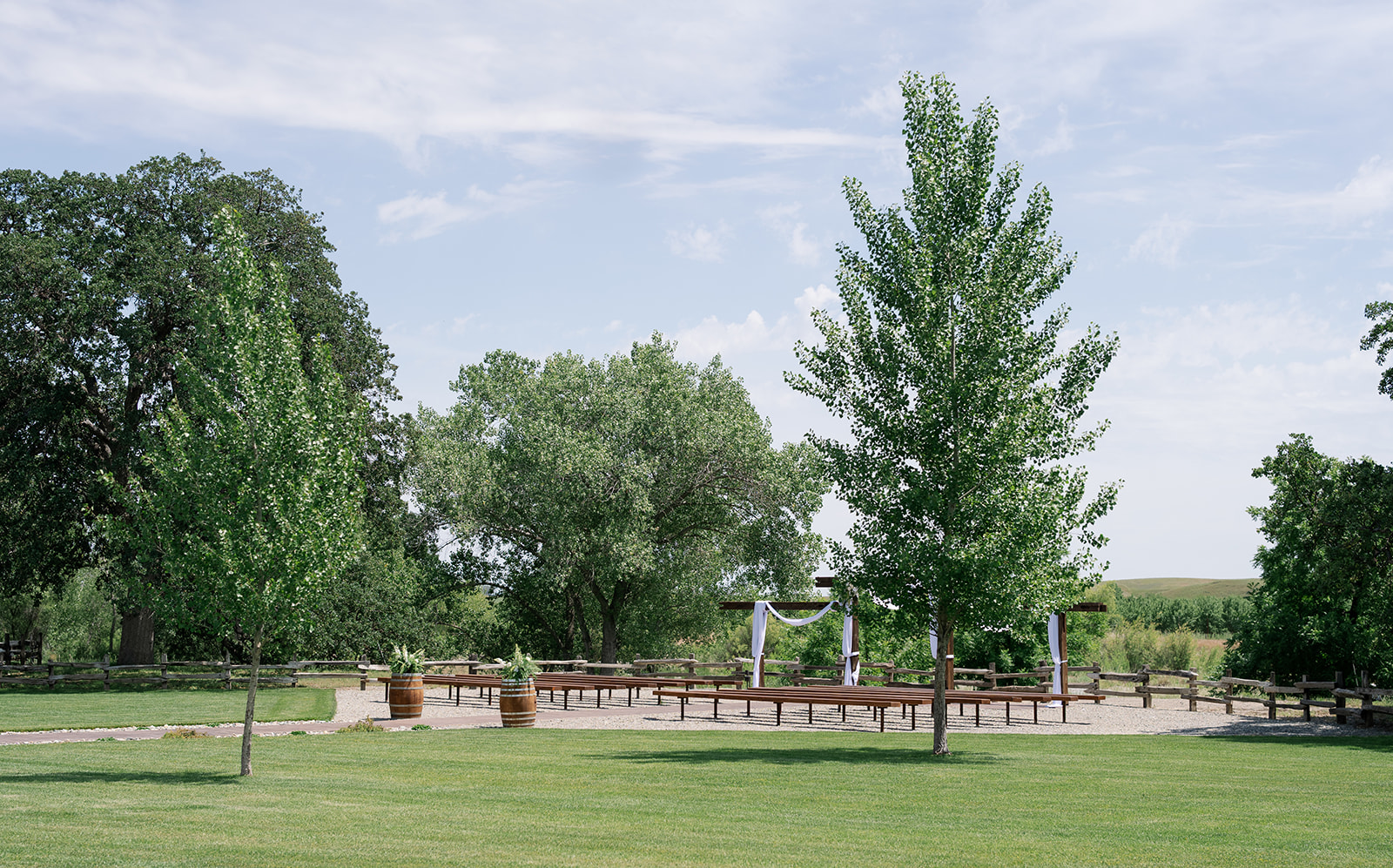 The ceremony lawn with draped arbor, bench seating and wine barrels